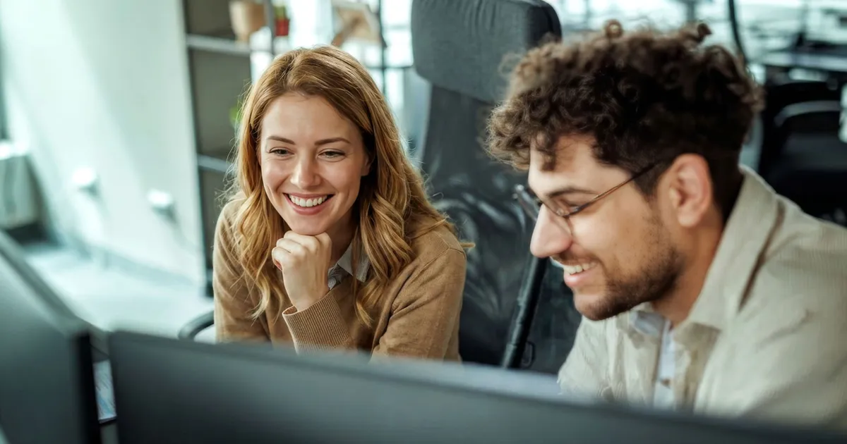 Two team members reviewing AI test automation results on a monitor in an office
